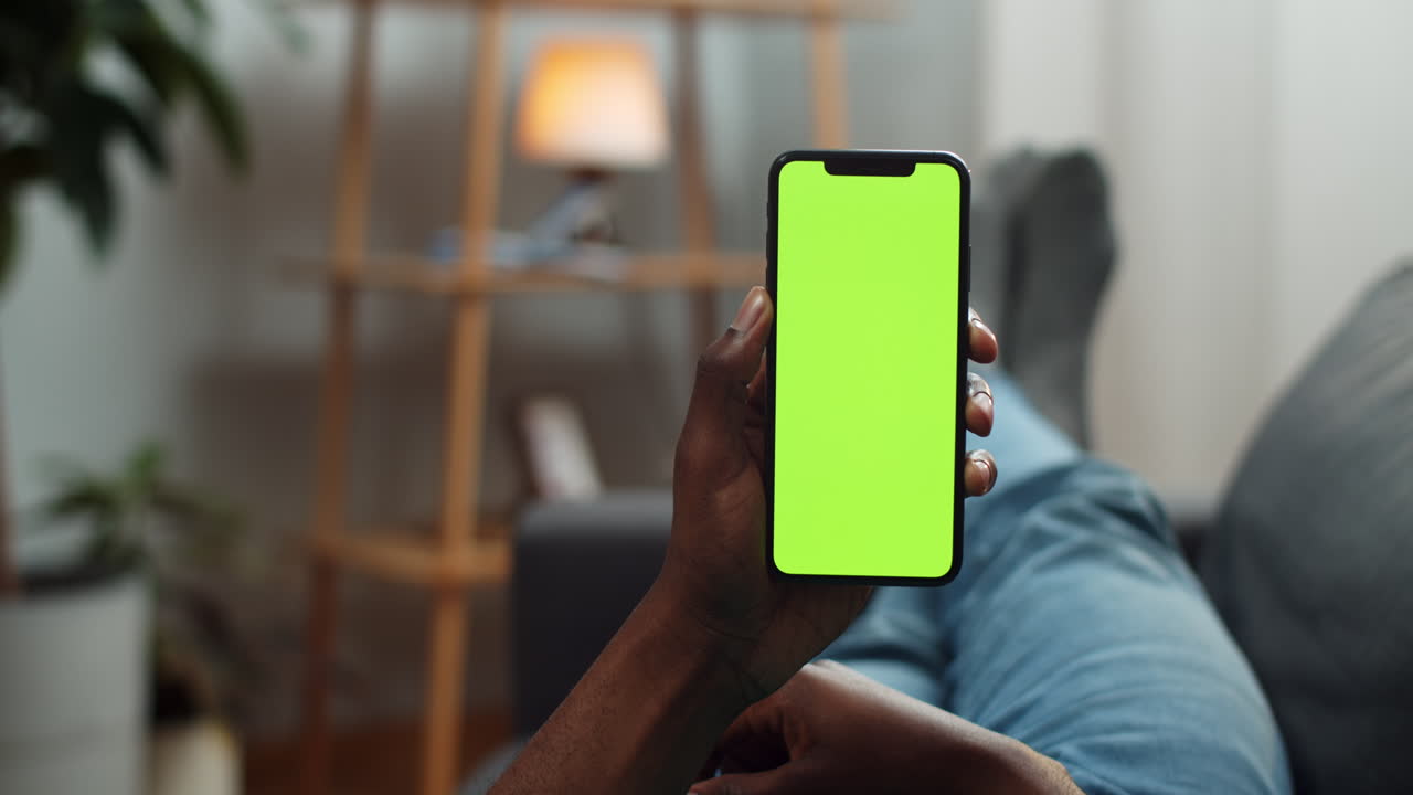 Smartphone with green screen held by a person on a couch