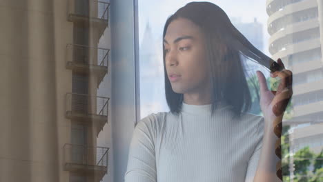 looking out window, thoughtful person observing city buildings in background