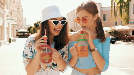 two happy friends enjoying drinks on the street