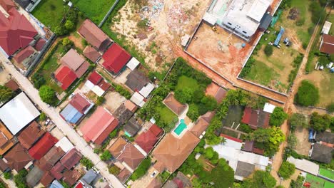 Top-down-aerial-perspective-of-the-Vientiane-cityscape-in-Laos,-revealing-vibrant-rooftops-adorned-over-the-residential-area,-portraying-the-concept-of-lively-urban-living-amidst-colorful-architecture