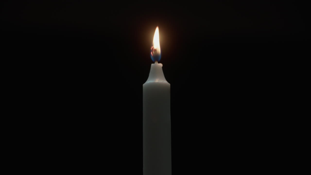Une bougie brûle dans la pièce sombre