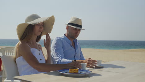 young man and woman drinking coffee on beach