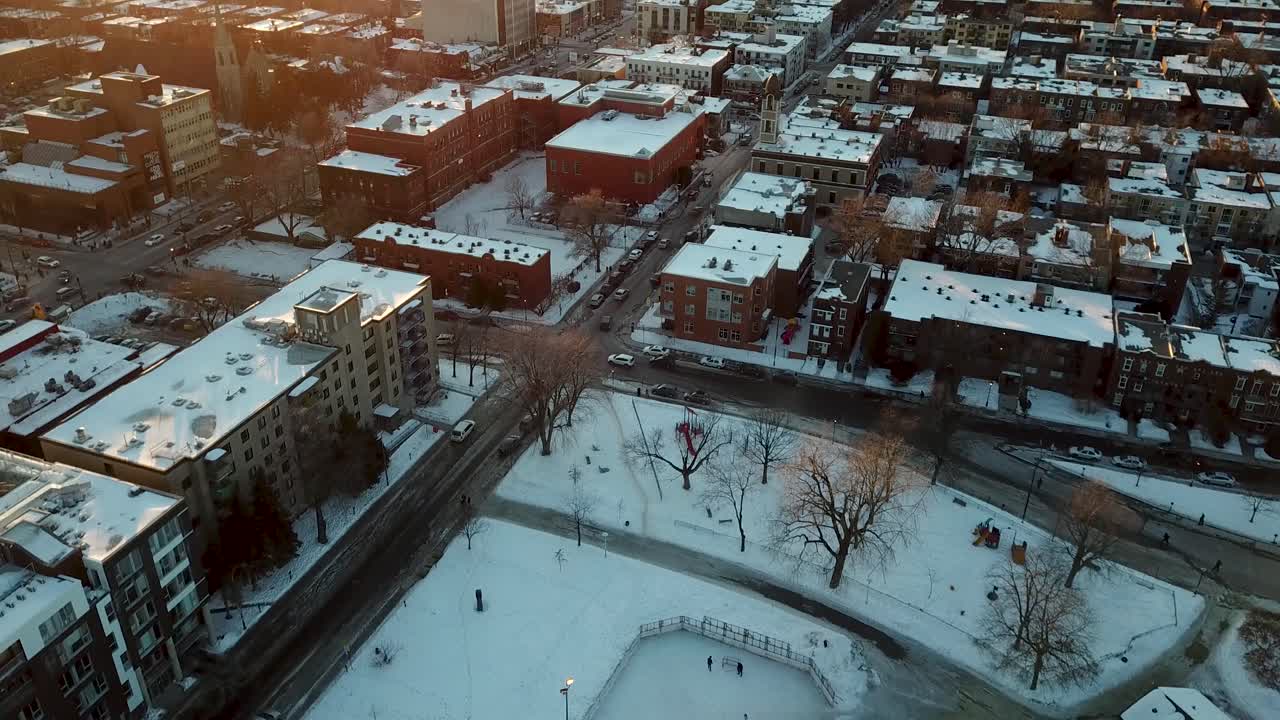 tomada panorámica aérea sobre una pista de hockey al aire libre en el invierno de montreal, revelando la gran ciudad y una hermosa puesta de sol