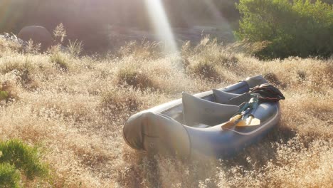 Close-up-of-inflated-raft-in-tall-grass-field,-golden-hour-with-copy-space