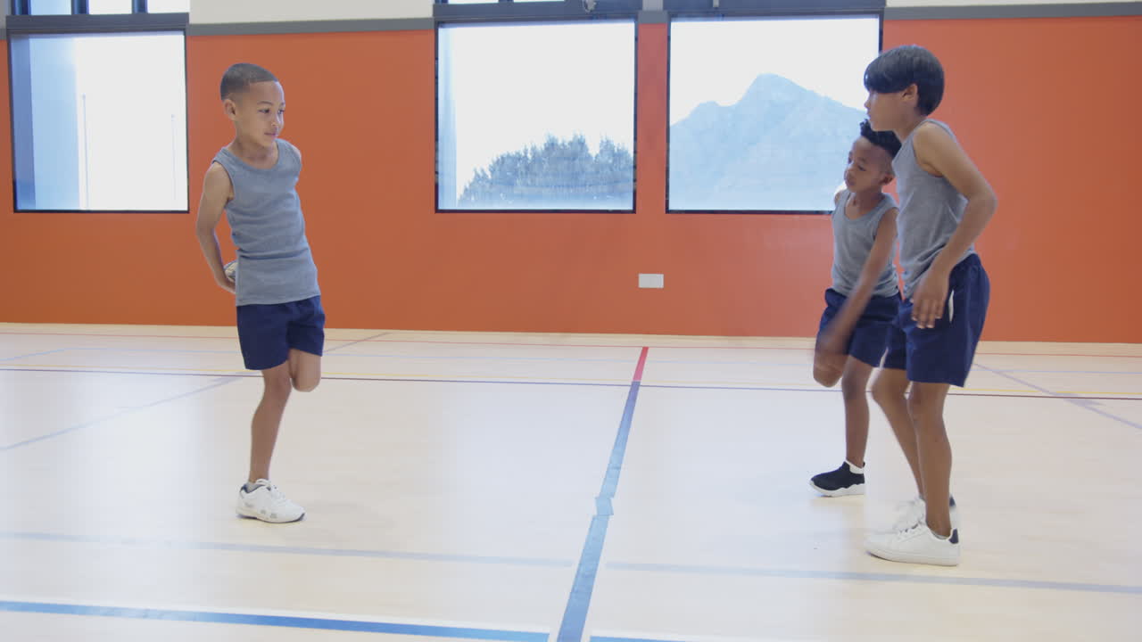 In school gym, three boys jumping rope and exercising together