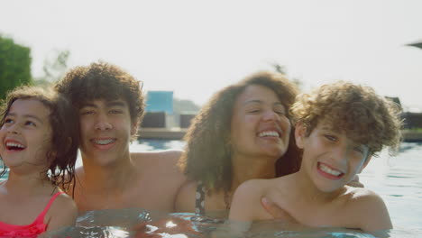 Retrato-De-Una-Familia-Multirracial-Relajándose-En-La-Piscina-Durante-Las-Vacaciones-De-Verano-Juntos