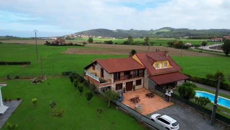 countryside house with a pool surrounded by green fields in cantabria. aerial view