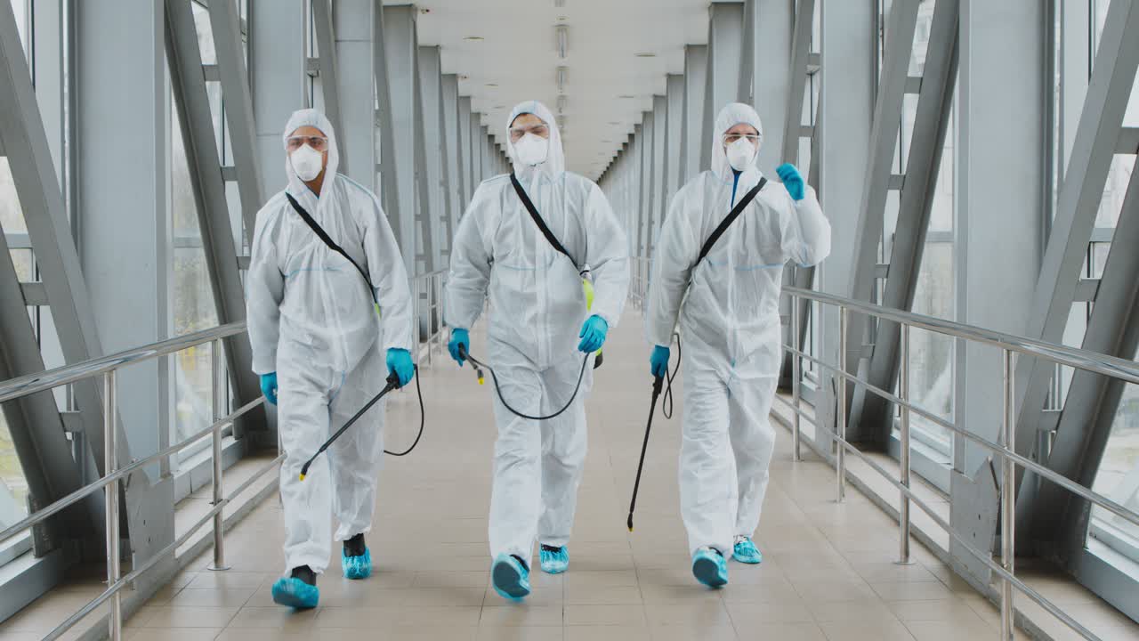 equipo de limpieza con equipo de protección desinfectando un puente