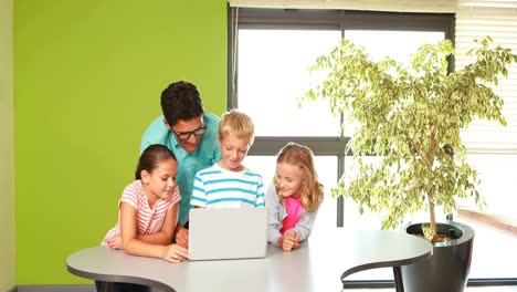 Teacher-and-kids-using-laptop-in-classroom