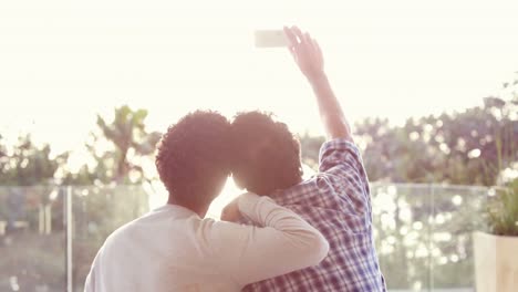 rear view of homosexual couple taking selfie