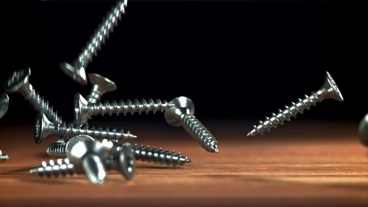 Close-up of Screws Falling onto a Wooden Surface in Slow Motion