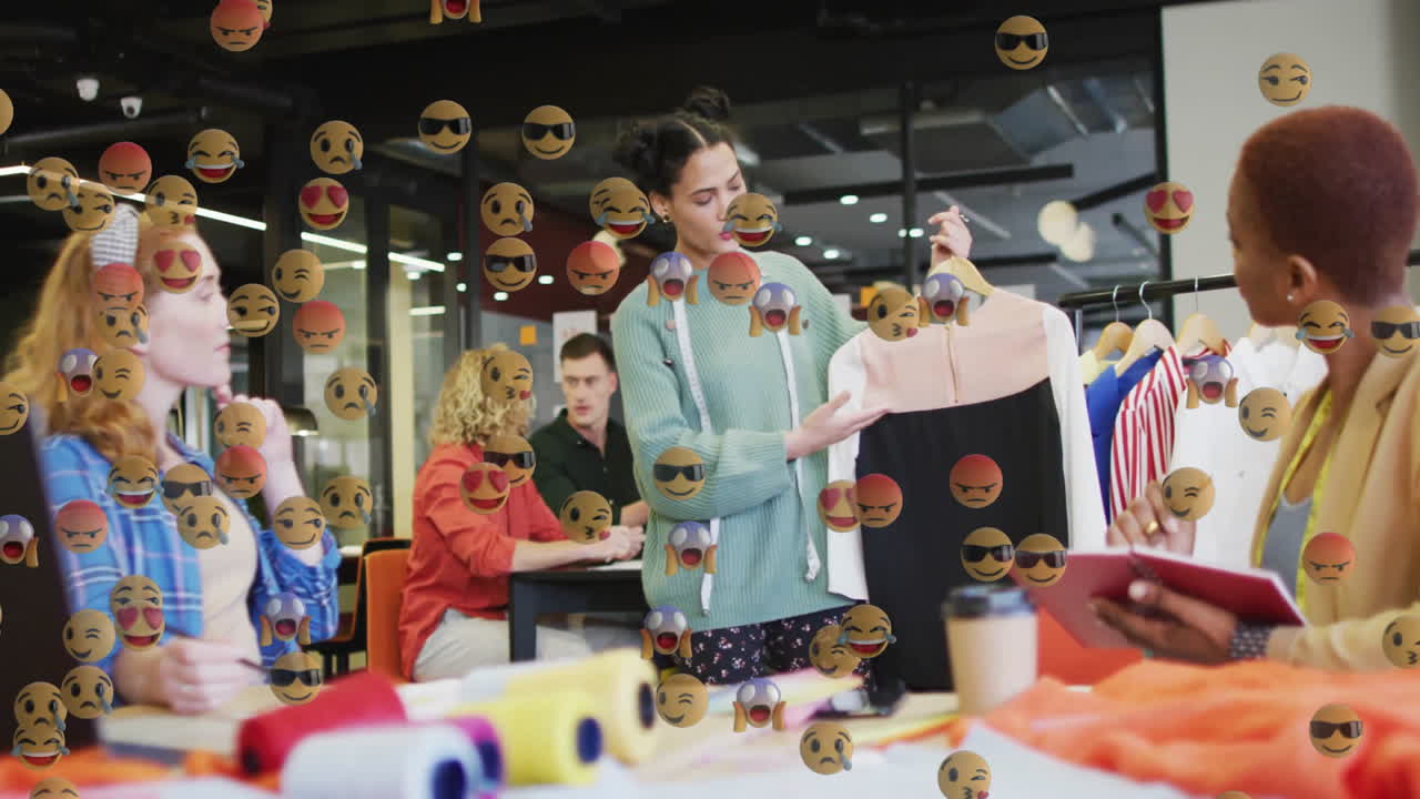Fashion designers gathering in studio arranging fabric rolls  and  dress sample, with emoji overlays