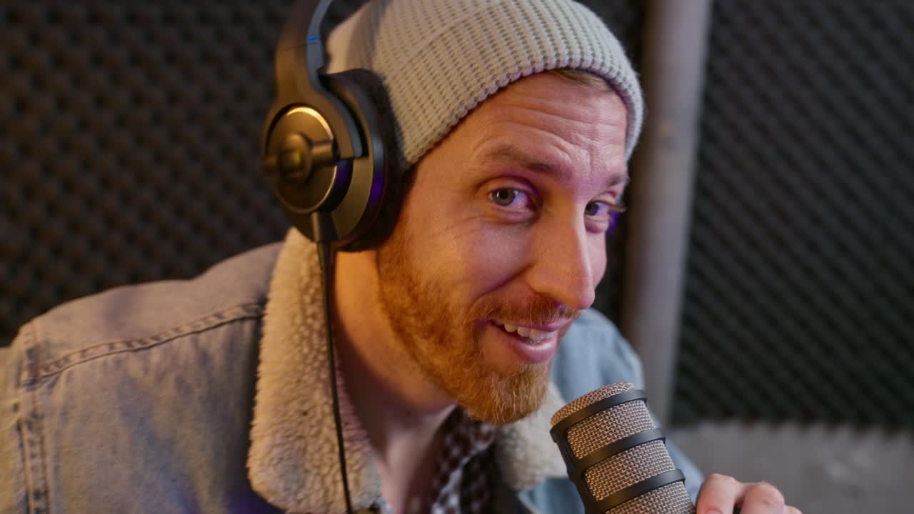 Podcast or radio host talking to camera on air or starting recording session in professional audio studio with microphone and console sound equipment. Influencer streaming asks to like and subscribe