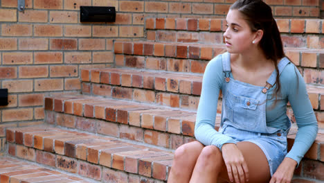 sad schoolgirl sitting alone on staircase