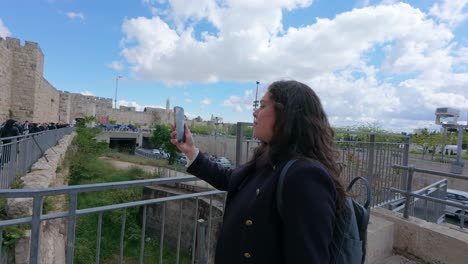 a woman is taking a picture of a cityscape with her cell phone. slow motion.