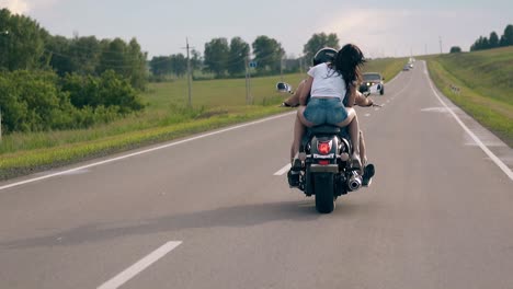 couple rides modern black motorbike against cars past field