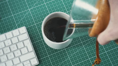 a young professional creative pouring hand brewed coffee at his work desk in home office