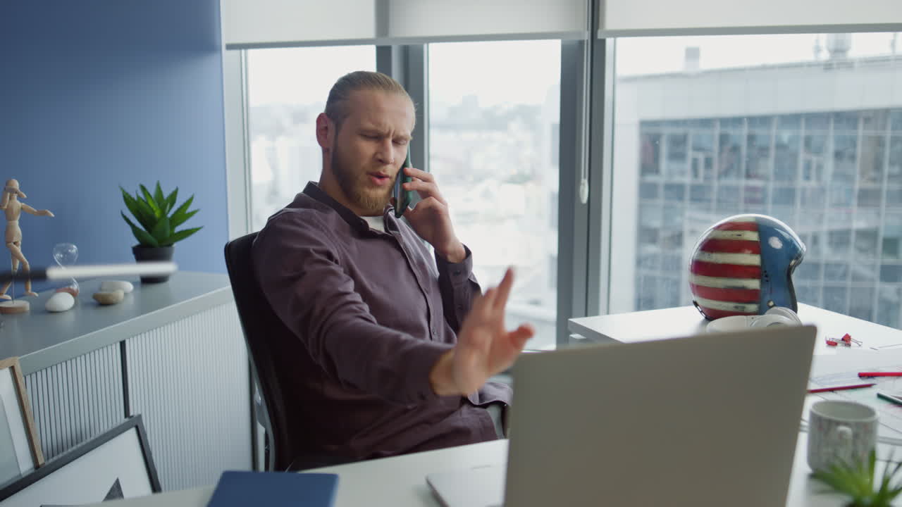 Primo piano di un ragazzo positivo che parla al cellulare in ufficio. Giovane uomo che sta conversando al suo smartphone.