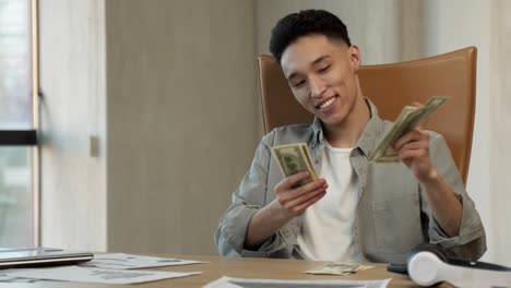 happy asian employee counts dollar bills at workplace