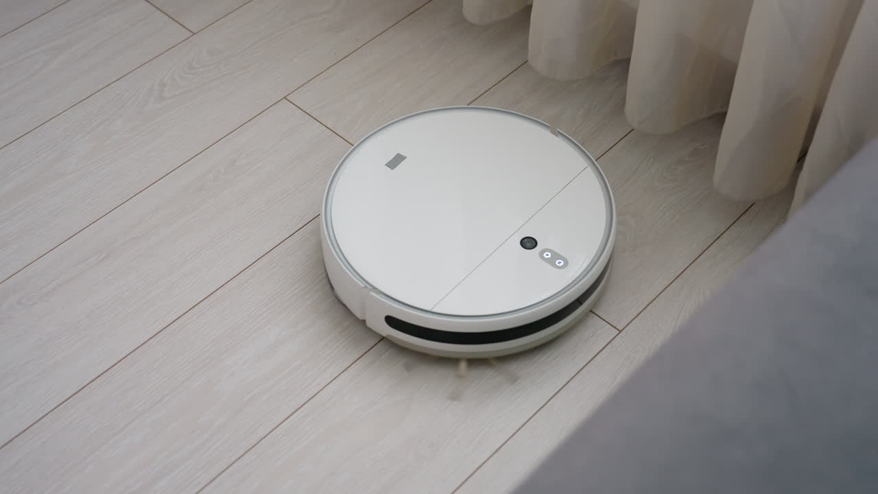 Robot vacuum cleaner rotates on light wooden floor during automated cleaning routine inside modern home interior, demonstrating smart navigation