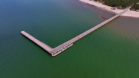 Aerial-view-a-bridge-standing-on-the-beach-of-Palanga,-which-goes-to-the-Baltic-Sea