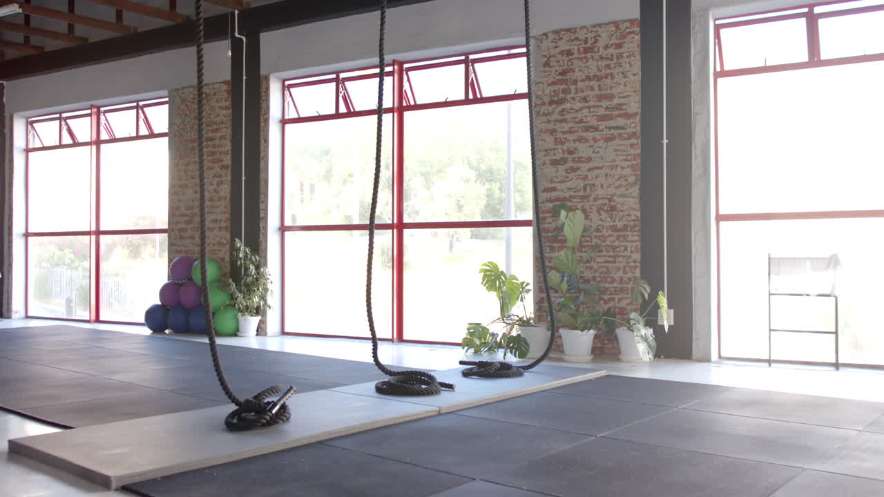 las grandes ventanas permiten que la luz del sol entre en el amplio gimnasio con cuerdas y esteras