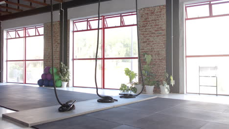 large windows let sunlight into spacious gym with ropes and mats