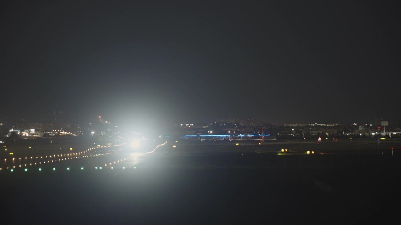 Pista aeroportuale di notte con luce di atterraggio dell'aereo e terminal.