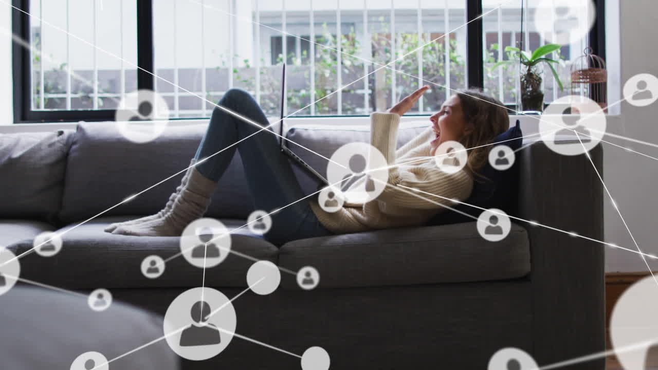 연결된 아이콘의 애니메이션, 코카시안 여성이 소파에 누워서 노트북을 사용하여 비디오 통화를하고 있습니다.