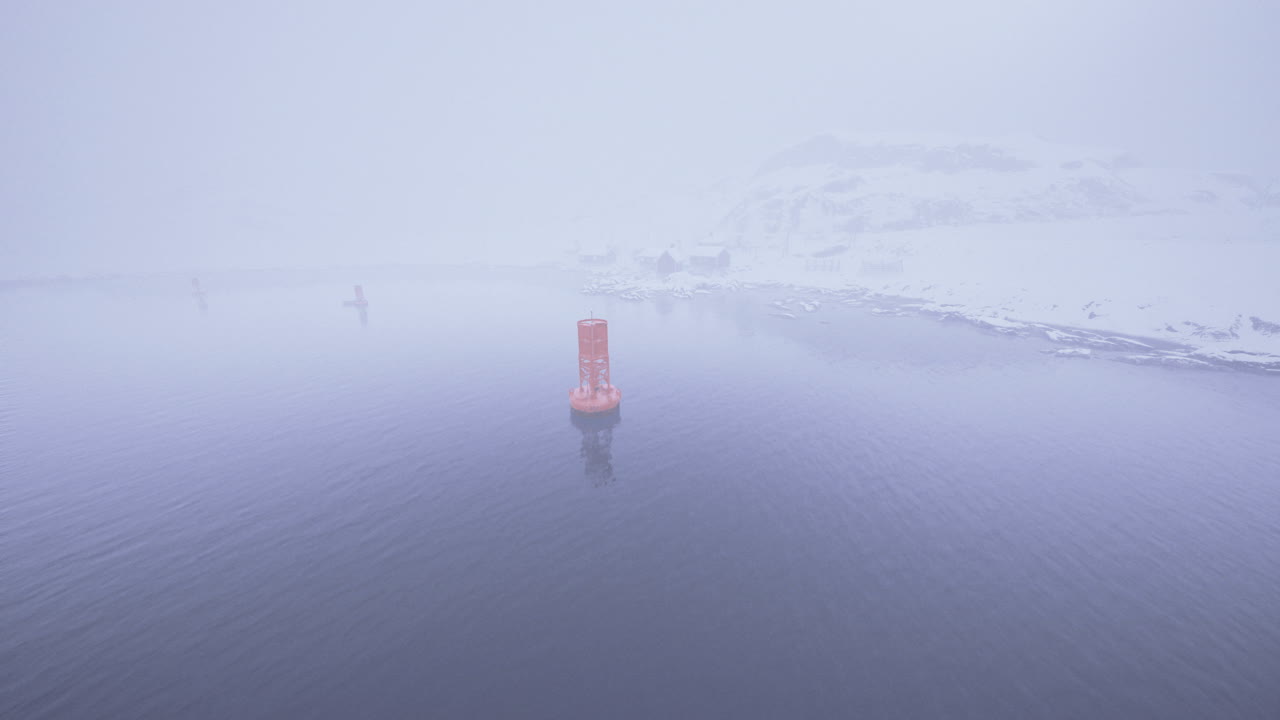 Foggy winter view of navigational buoy in cold waters
