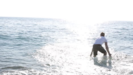 young man playing in the water at the sunny beach