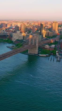 two huge bridges crossing east river. flying over the blue waters flowing through the fantastic new york city. vertical video