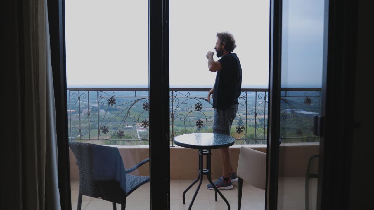 hombre tomando café en un balcón con vistas