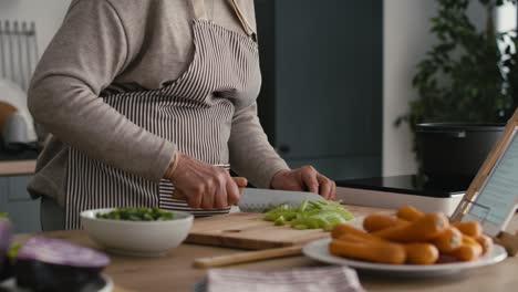 unrecognizable caucasian senior woman peeling a carrot while cooking in the kitchen