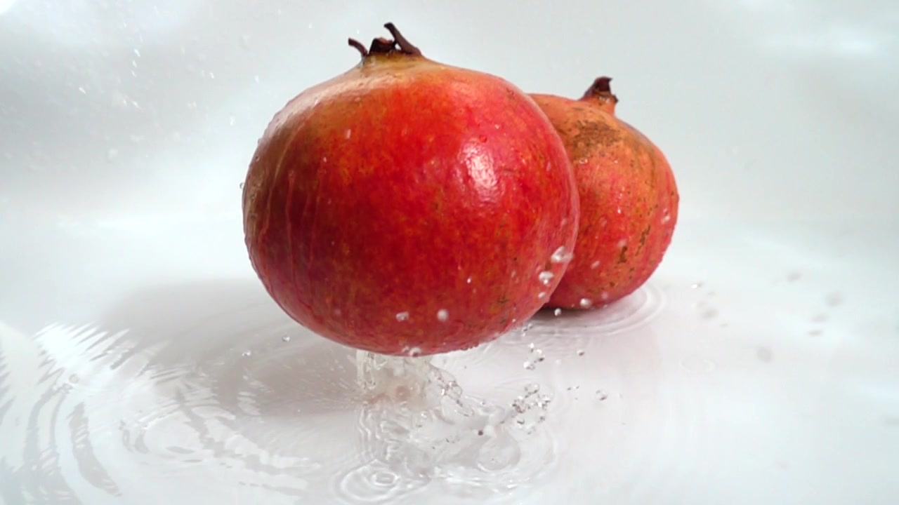 Granatæble falder i vandet. Slow motion