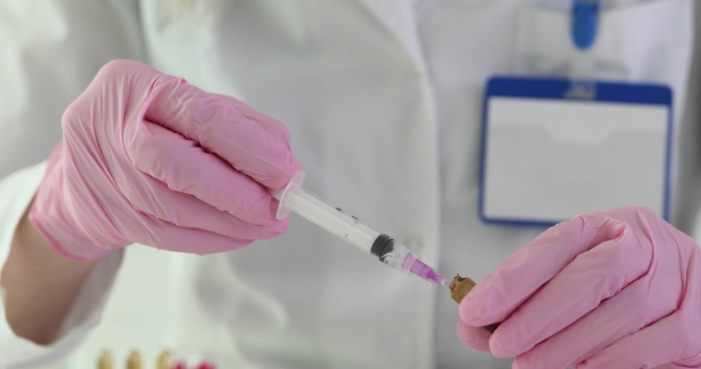 Medico con guanti preleva medicinale da ampolla con siringa