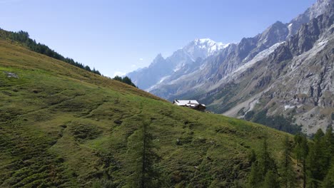 drone shot flying past a mountain cabin in the italian alps to reveal a valley