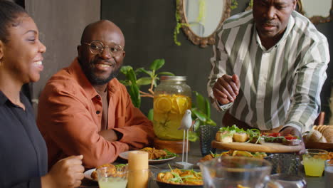 black man serving food for guests at home family dinner