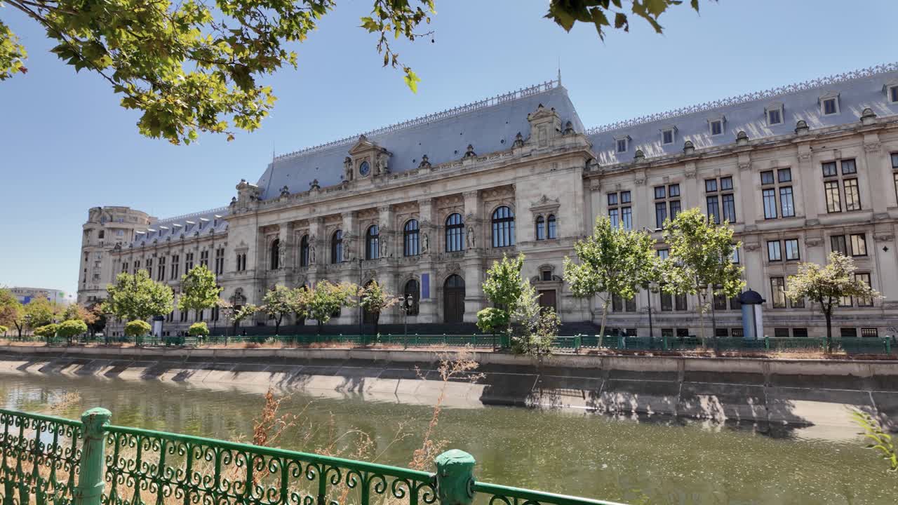 Prise de vue panoramique de la Cour d’appel partiellement encadrée par le feuillage, mettant en valeur les détails architecturaux à Bucarest, en Roumanie