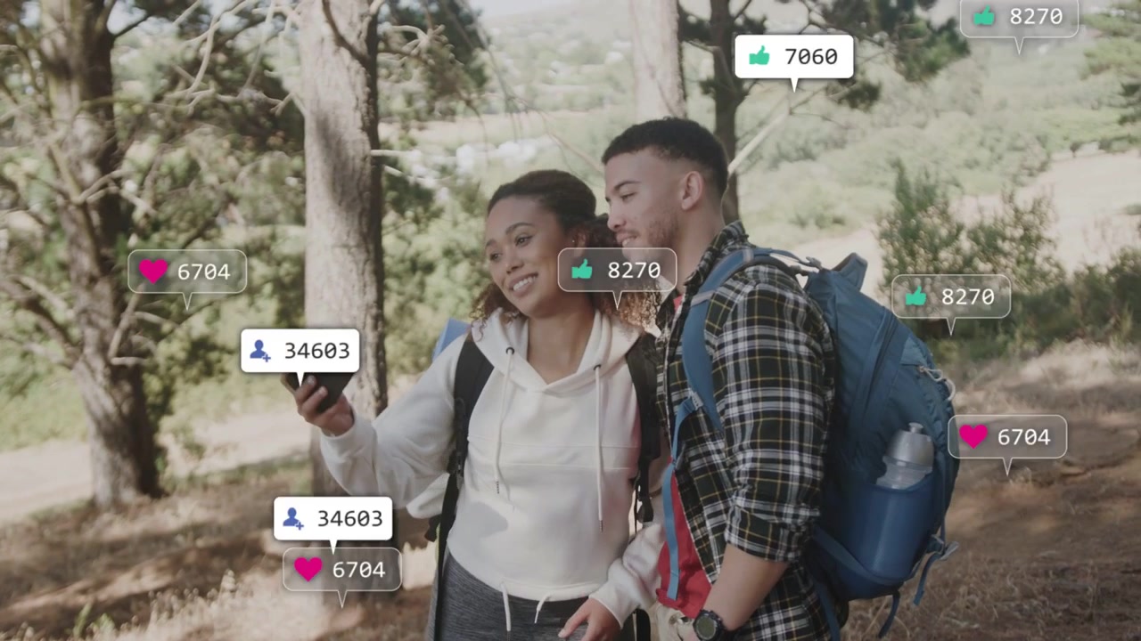 Akıllı telefonunu kontrol eden çift, etraflarında çoğalan sosyal medya simgelerini izliyor ve etkileşim için poz veriyor.