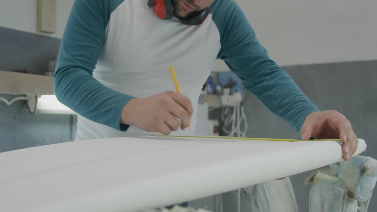 мужчина, делающий доски для серфинга, в своей мастерской