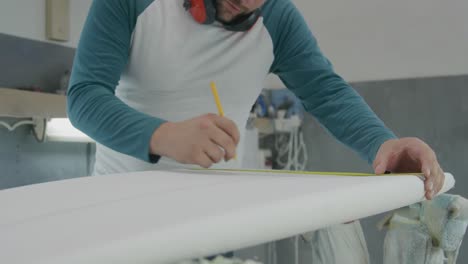 un hombre que hace tablas de surf en su taller