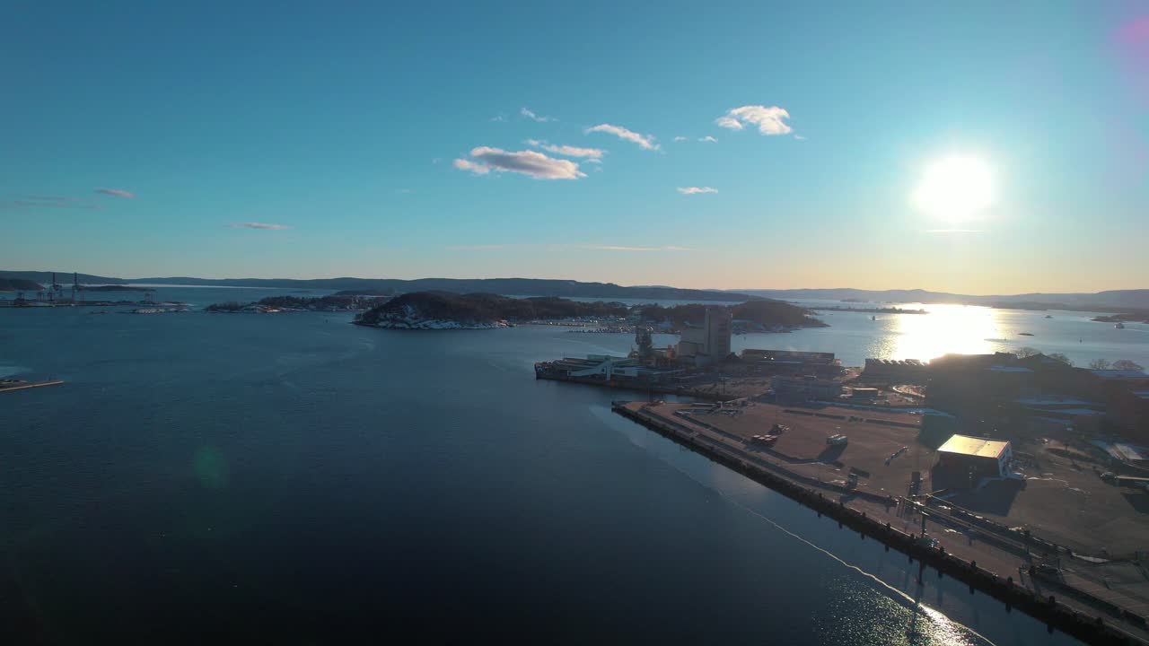 drone aéreo hacia adelante disparado sobre la vía fluvial de la entrada del oslofjord con el sol surgiendo en el fondo en oslo, noruega durante la mañana