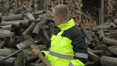 lumberjack in reflective jacket. man woodcutter with huge axe. sawn logs, firewood background