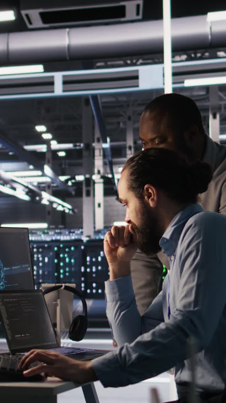 Vertical video Data center engineers use laptop, collaborating on doing AI software updates