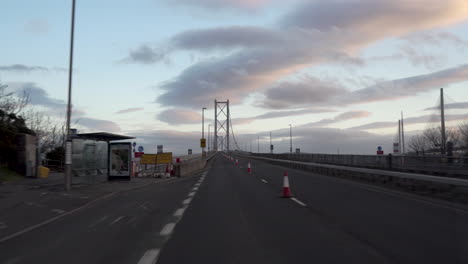 motion shot from a vehicle crossing a forth road bridge with wonderful sunset light and clouds in edinburgh, scotland