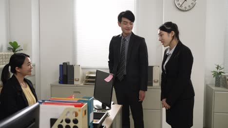 asian male manager introducing young intern to a colleague with hand gesture on first day at work in the office. the friendly female welcomes the newcomer