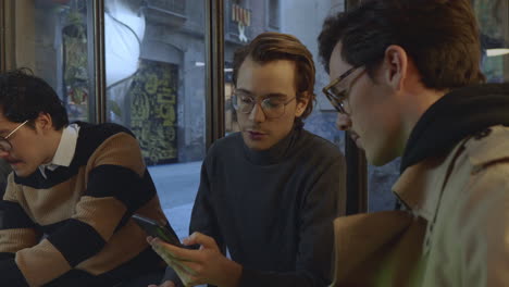 Cheerful businessman showing colleague information on smartphone screen.