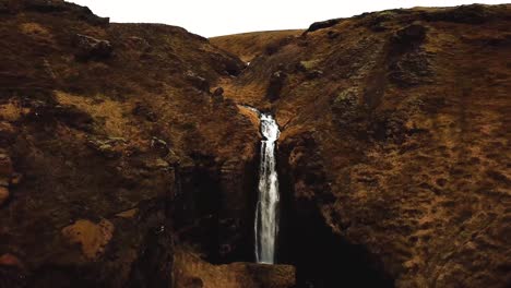 Aerial-view-of-water-flowing-down-a-waterfall-in-Iceland,-during-winter-time