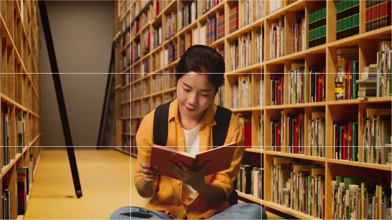 pantalla tomó la foto de una estudiante asiática con una mochila sosteniendo y leyendo un libro mientras estaba sentada en la biblioteca
